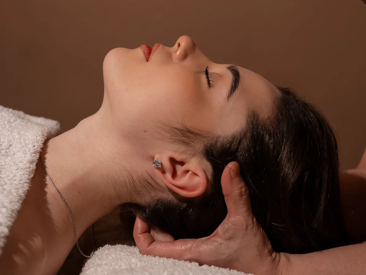 Žena relaxuje při masáži hlavy a obličeje se zavřenýma očima