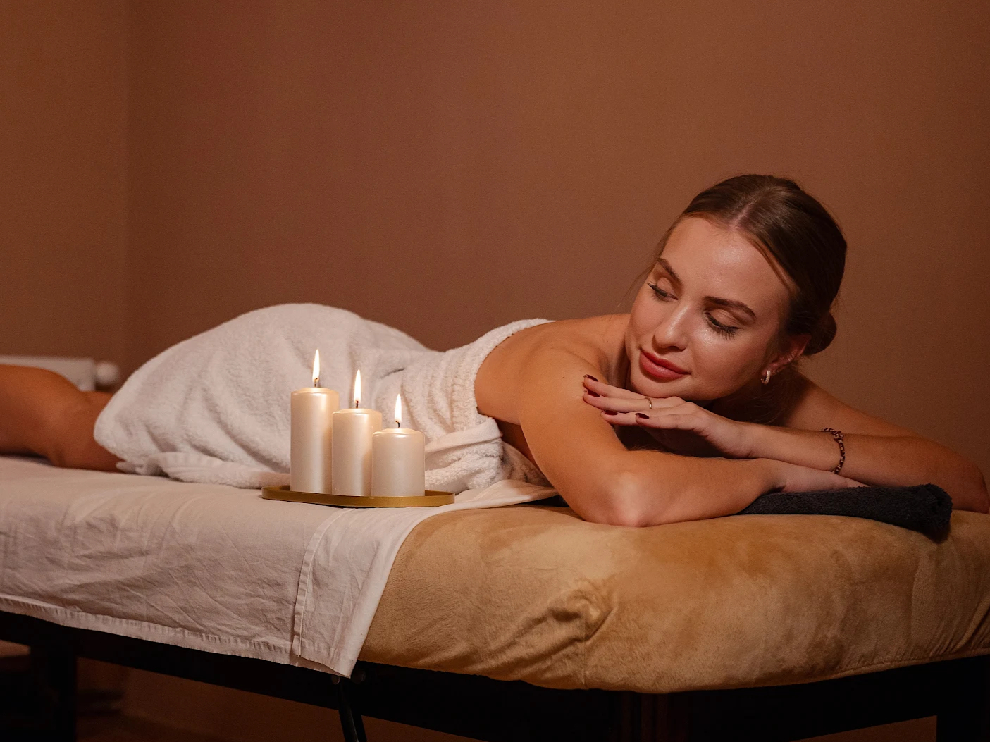 Žena relaxuje při párové masáži při svíčkách v masážní místnosti